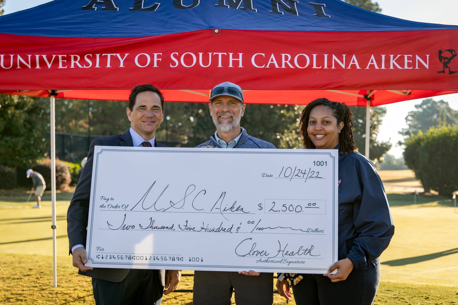 Chancellor Hiemmermann and Carmen Williams, Alumni Director pose with Clover Health representative