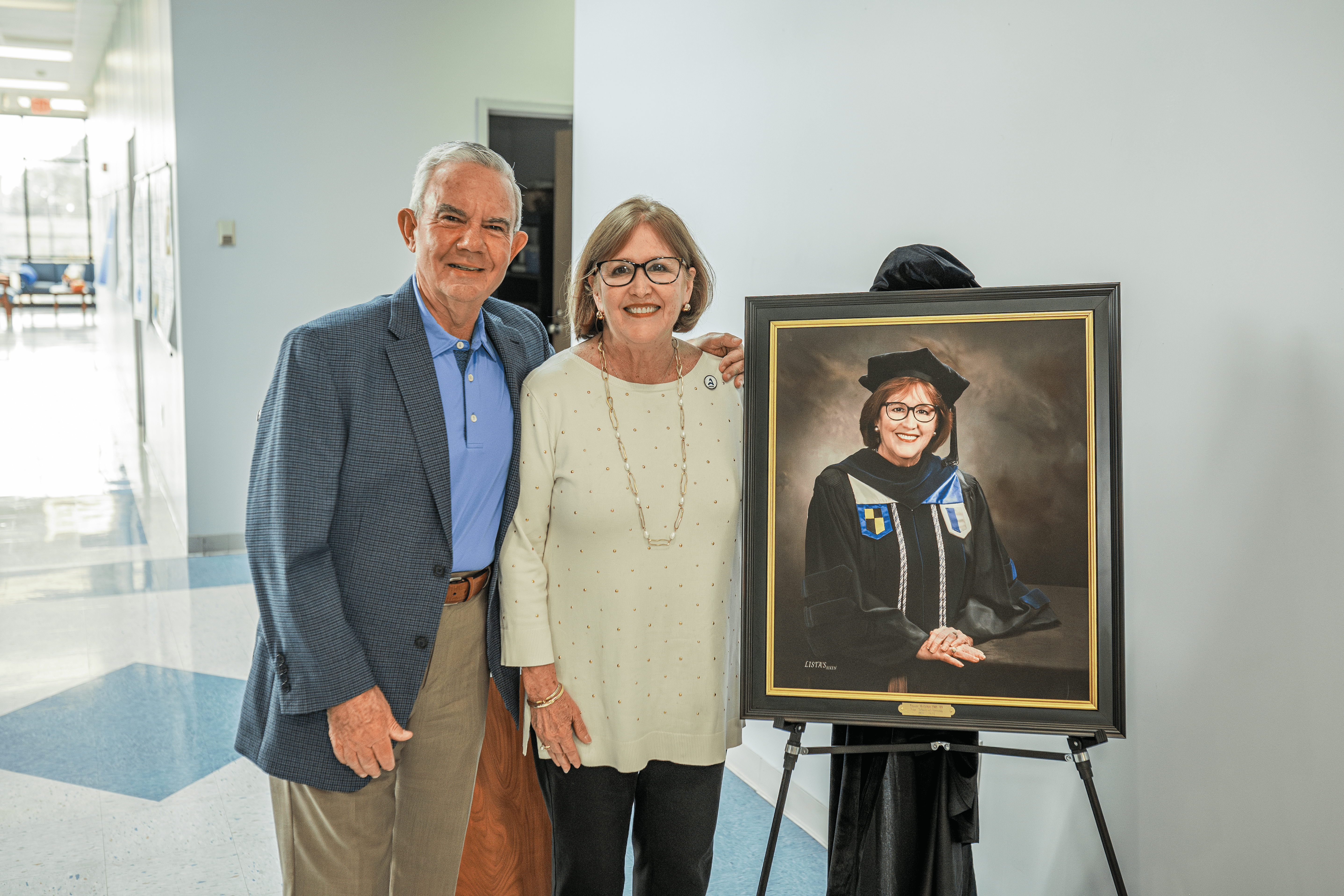 Dr. Thayer McGahee stands with her husband beside new portrait that will be hung in the School of Nursing