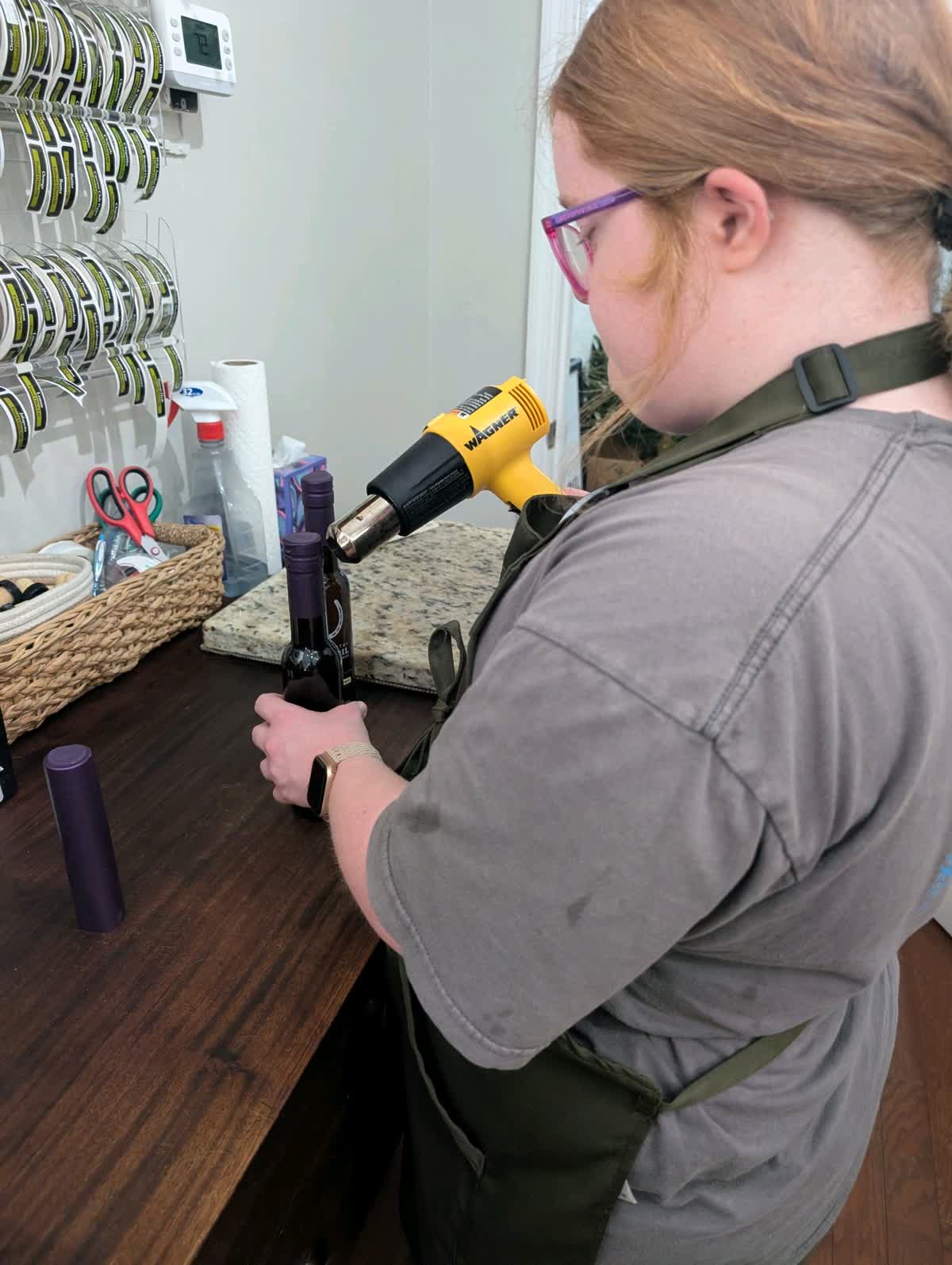 LIFE Student using a heat gun to seal bottles of olive oil.